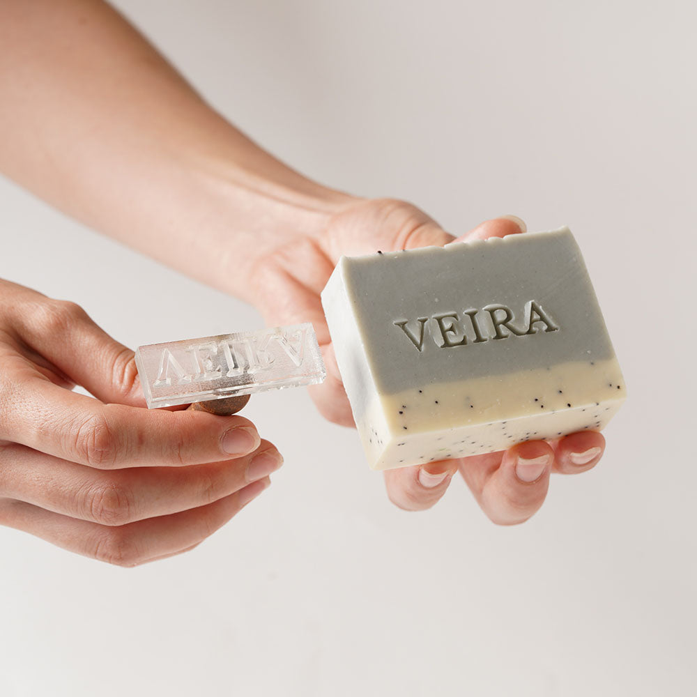 Custom soap stamp creating a clear brand impression on a green handmade soap bar.