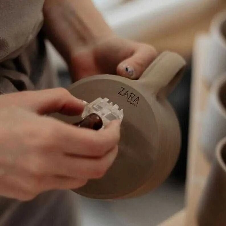Person using custom pottery stamp to imprint logo on clay cup handle